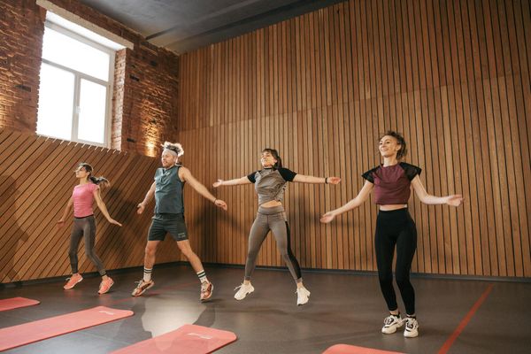 Happy group of people doing aerobic exercises together indoors.